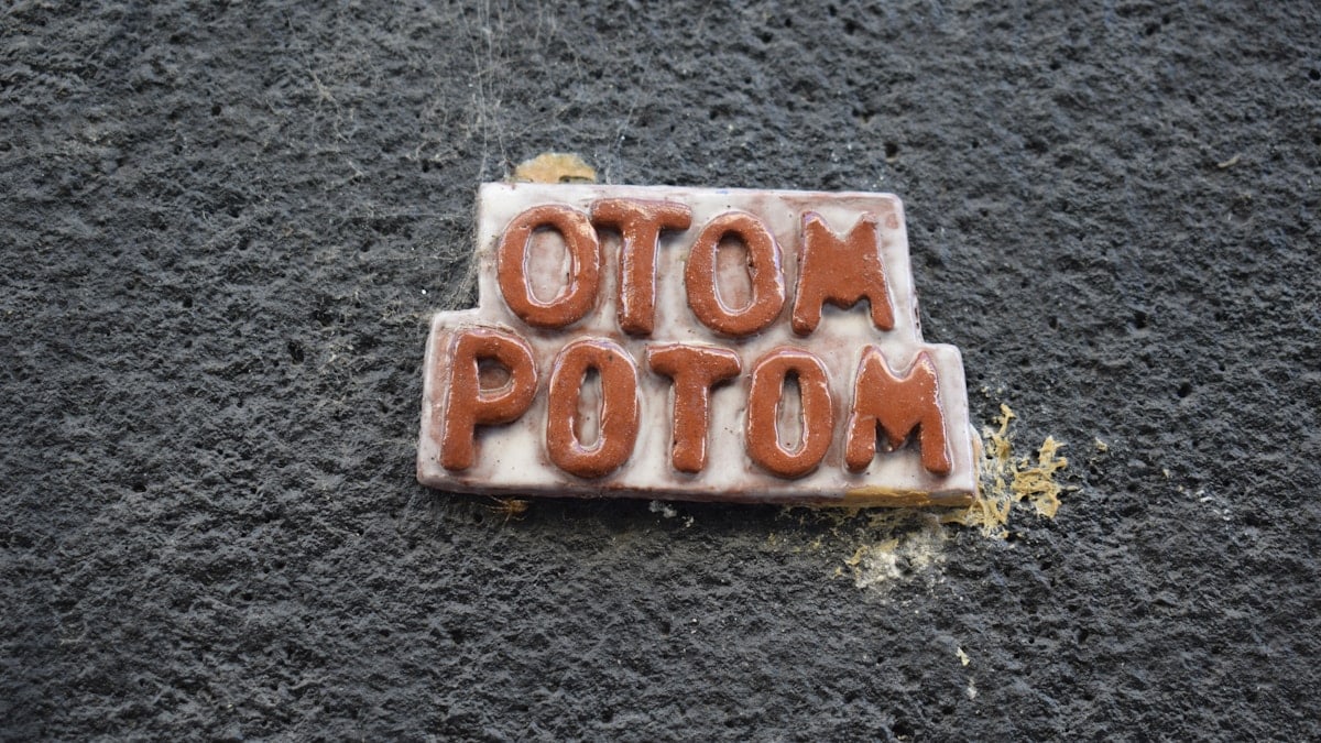 Brown letters spelling otom potom on a plaque.